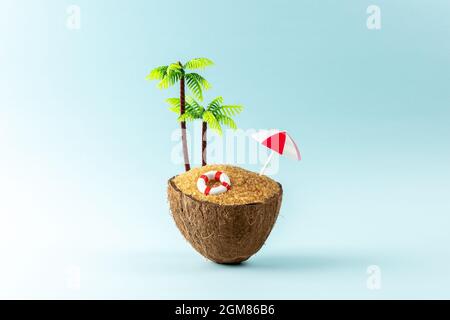 Spiaggia tropicale con frutta di cocco e ombrellone. Sfondo estivo minimo e creativo. Foto Stock