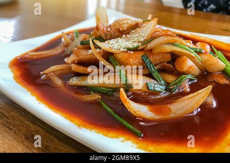 Delizioso tteokbokki piccante coreano. L'immagine di tteokbokki piccante su sfondo di legno Foto Stock