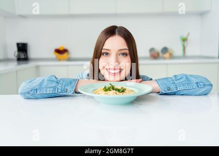 Foto ritratto ragazza sorridente affamato vicino piatto con pasta in cucina Foto Stock