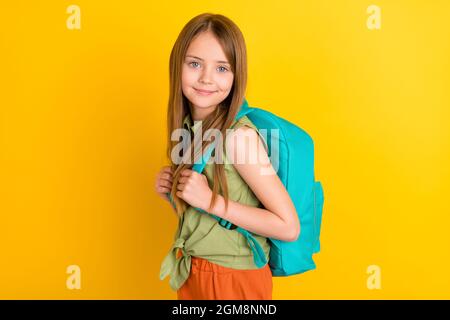 Foto ritratto scolgirl indossare camicia verde andare a scuola con zaino isolato colore giallo brillante sfondo Foto Stock