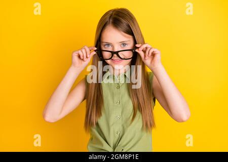 Foto ritratto scolgirl indossare camicia verde togliere occhiali sorridenti isolato colore giallo brillante sfondo Foto Stock