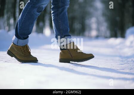 Passi lungo il sentiero innevato. Un uomo cammina nel parco in inverno. Foto Stock