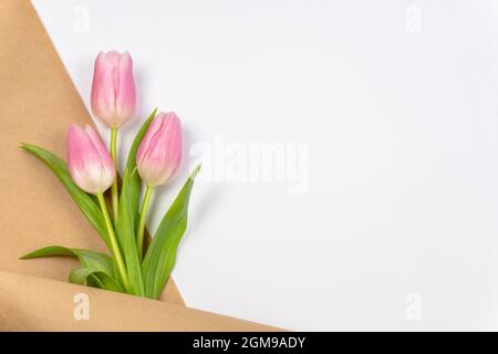 Tulipani rosa in carta artigianale su sfondo bianco con spazio di copia o logo. Pasqua. San Valentino. Il giorno della madre. Vista dall'alto Foto Stock