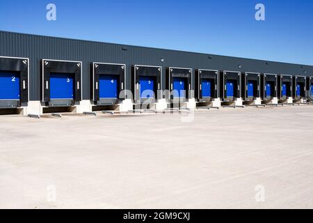 Fila di banchine di carico con porte a serranda in corrispondenza di un magazzino industriale. Foto Stock