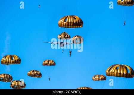 Paracadutisti militari paracadutisti paracadutisti che saltano fuori da un aereo di forze aeree in una giornata di cielo blu chiaro. Foto Stock