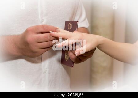 Lo sposo mette l'anello di nozze sul dito della sposa. Foto Stock