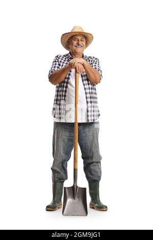 Ritratto a tutta lunghezza di un contadino maturo appoggiato su una pala e sorridente isolato su sfondo bianco Foto Stock