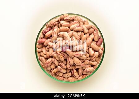 Vista dall'alto dei fagioli secchi pinto in un recipiente di vetro isolato su bianco. Versate di fagioli. Foto Stock