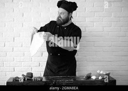 Barbuto chef lo chef prepara i pasti al tavolo in cucina Foto Stock