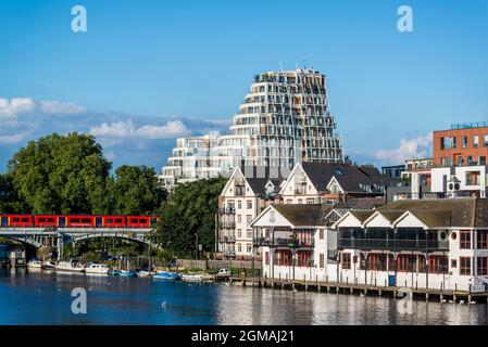 Edifici lungo il fiume Kingston e treno che passa sopra il ponte, Kingston-upon-Thames, Surrey, Inghilterra, Regno Unito Foto Stock