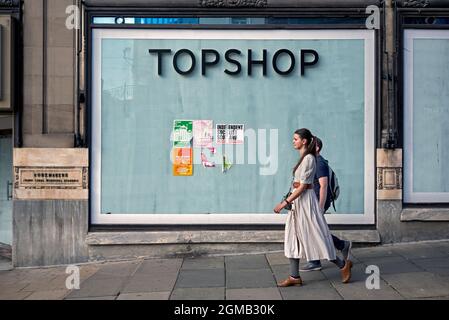 Coppia a piedi da un ramo chiuso di Topshop su Princes Street, Edimburgo, Scozia, Regno Unito. Fa parte del fallito gruppo Arcadia. Foto Stock