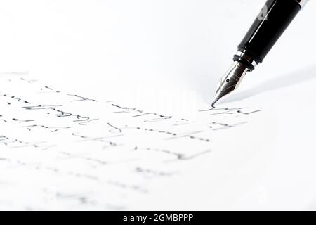 La penna stilografica nera sta scrivendo una lettera o un manoscritto su un foglio bianco, spazio di copia, primo piano con fuoco selezionato e profondità di campo ridotta Foto Stock