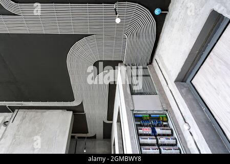 Cavi elettrici e scatola interruttori su soffitto e parete in cemento. Moderni tubi in plastica con fili in camera. Linee di tubi di cablaggio in pvc dopo il professi Foto Stock