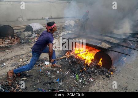 Dhaka, Bangladesh. 17 settembre 2021. DHAKA, BANGLADESH - 17 SETTEMBRE 2021: Un lavoro stradale migrante fonde i minerali di asfalto su piccole pietre per fare una miscela come parte del ripavimentamento di una strada in uno dei sobborghi di Dhaka, i dipendenti lavorano duramente diverse ore al sole per mantenere le strade e le strade della città in buone condizioni. Il 17 settembre 2021 a Dhaka, Bangladesh. (Foto di Tanvir Ahammed/ Eyepix Group) Credit: Eyepix Group/Alamy Live News Foto Stock