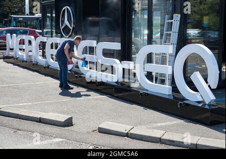 Bucarest, Romania - 15 settembre 2021: Un dipendente che pulisce la pubblicità per il nuovo Pop-Up Store Mercedes-EQ che sarà aperto in Piazza Victoriei Foto Stock