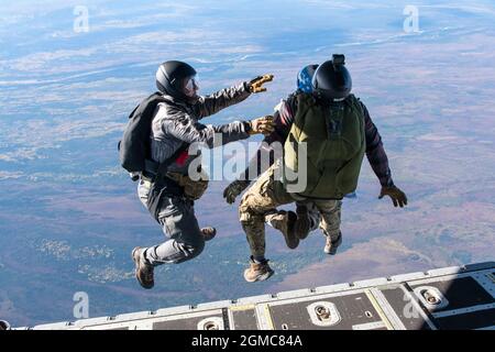 Alaska Air National Guard pararescuemen assegnati al 212th Rescue Squadron condurre un salto in tandem da un AKANG HC-130J Combat King II assegnato al 211th Rescue Squadron sopra Alaska, 9 settembre 2021. Lo squadrone di salvataggio svolge una formazione regolare per mantenere la disponibilità operativa per le missioni civili di ricerca e salvataggio, nonché per le operazioni di emergenza. I salti in tandem reali sono necessari in situazioni in cui sono necessari salti non qualificati, come i medici, per le operazioni di recupero. (Foto delle forze aeree degli Stati Uniti di Senior Airman Emily Farnsworth) Foto Stock