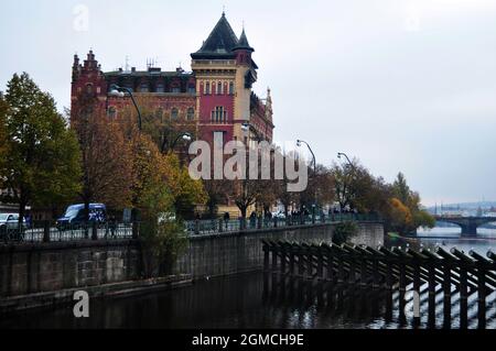 Visualizza paesaggio urbano classico vintage retro antico edificio con tronco diga di sbarramento in legno e barca barriera di legno nel fiume Moldava a Praha città Foto Stock