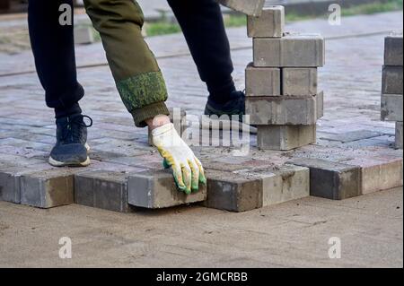 posa di lastre di pavimentazione sulla sabbia con le mani Foto Stock