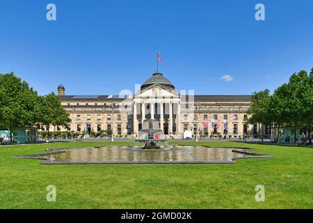 Wiesbaden, Germania - Luglio 2021: Centro convegni chiamato 'Kurhaus' con parco e fontana in giorno di sole Foto Stock