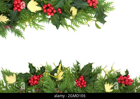 Solstizio d'inverno tradizionale, Natale e Capodanno sfondo bordo su bianco con agrifoglio, cedro, edera e vischio. Disposizione piatta, vista dall'alto, spazio di copia. Foto Stock