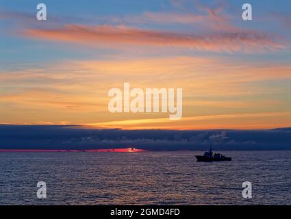 Dawn sopra il campo di Alvheim nel Mare del Nord Norvegese con una nave da Escort sismica che si affaccia contro il Sole nascente. Foto Stock