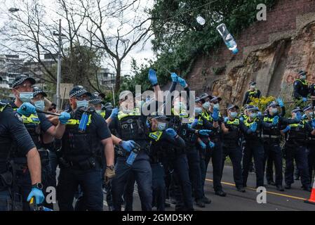 Melbourne, Australia. 18 settembre 2021. Un ufficiale di polizia oscilla il suo batone nel tentativo di fermare una bottiglia d'acqua volante. Credit: Jay Kogler/Alamy Live News Foto Stock