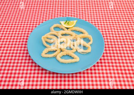 Tipica tapa spagnola di anelli di calamari martoriati con farina di grano e uova fritte in olio d'oliva su un piatto blu Foto Stock