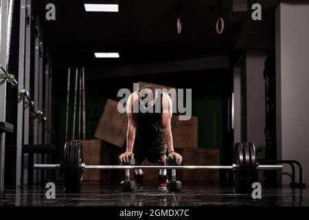 Atleta muscolare con pesi. Riscaldamento davanti a un pesante barbell. Foto Stock