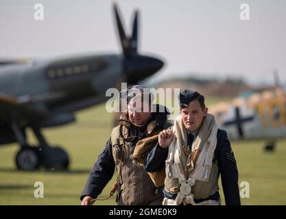 IWM Duxford, Cambridgeshire, Regno Unito. 18 settembre 2021. Primo giorno della Battaglia di Gran Bretagna Air Show a IWM Duxford, l'ex sito RAF che ha svolto un ruolo centrale come base per molti dei piloti Spitfire e uragano durante la seconda guerra mondiale. Le grandi folle guardano il re-enattore equipaggio di volo a piedi oltre una fila di Spitfire parcheggiati. Credit: Malcolm Park/Alamy Live News Foto Stock