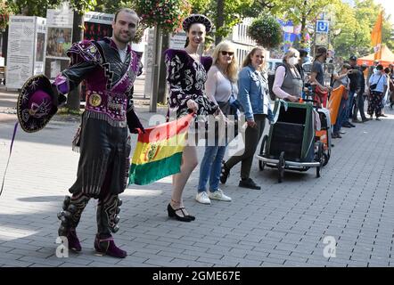 Duisburg, Germania. 18 settembre 2021. I ballerini dell'associazione 'amici della Bolivia' formano una catena umana insieme ai cittadini di Duisburg nel centro della città. Le organizzazioni avevano chiesto l'azione "Rescue Rings for Human Rights" (anelli di salvataggio per i diritti umani). Già nel 2020, un'azione a livello nazionale consisteva nel formare una catena di salvataggio da Amburgo, passando per Stoccarda, al Mar Mediterraneo, al fine di richiamare l'attenzione sui diritti umani dei rifugiati alle frontiere esterne dell'Unione europea e nel Mar Mediterraneo. A causa di Corona, gli anelli di salvataggio sono ora in fase di formazione al posto di una catena umana. Credit: Roberto Pfeil/dpa/Alamy Live News Foto Stock