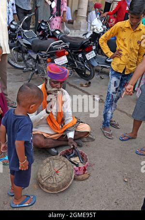 Beawar, India. 16 settembre 2021. Un incantatore di serpenti con un serpente intrattiene i bambini fuori dal tempio della divinità popolare di Veer Teja durante il festival Teja Dashami a Beawar. I serpenti sono adorati come divinità in India. (Foto di Sumit Saraswat/Pacific Press) Credit: Pacific Press Media Production Corp./Alamy Live News Foto Stock