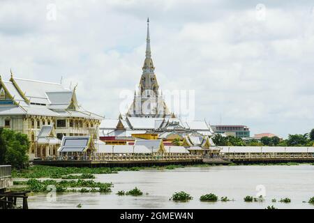 CHACHOENGSAO, THAILANDIA – 27 MAGGIO 2018: Vista di Wat Sothonwararam al sole dall'altro lato del fiume Bang Pakong con molte persone sul lungofiume Foto Stock