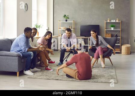 Gruppo di giovani amici che raccontano storie mentre si siedono insieme nel soggiorno Foto Stock