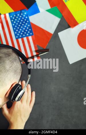 Imparare le lingue straniere. Corsi di lingua audio. Sfondo delle bandiere dei paesi e delle cuffie sul tavolo. Foto Stock