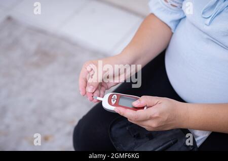 Donna incinta controllo del sangue rischio livello di zucchero per gestazionale. Sesso femminile gravidanza salute glucometro concetto di misurazione del glucosio per glucometro, medico Foto Stock