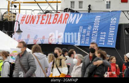 Rostock, Germania. 18 settembre 2021. Al rally finale dopo la dimostrazione dell'alleanza statale #unteilbarMV, un grande banner con l'iscrizione '#UNTEILBARMV' appende su una nave tradizionale. Secondo l'organizzatore, circa 2000 persone hanno partecipato alla manifestazione, la polizia ha parlato di circa 1000 partecipanti. Si suppone che la manifestazione sia di pari opportunità, di protezione del clima e di ogni forma di discriminazione, fascismo e odio. Credit: Bernd Wüstneck/dpa-Zentralbild/dpa/Alamy Live News Foto Stock