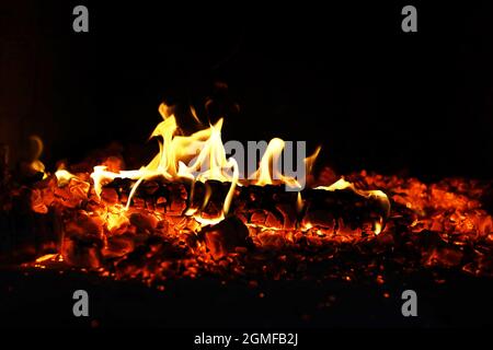 Scintille calde rosse che bruciano volano dal fuoco grande. Bel sfondo astratto sul tema del fuoco. Carboni brucianti, particelle infiammate che volano contro la colpa Foto Stock