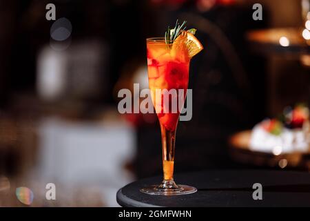 Cocktail alcolici esotici freschi e colorati con arancia e rosmarino al banco del bar. Bevanda analcolica gustosa con frutta. Fuoco selettivo. Foto Stock