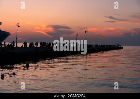 molo audace a Trieste con silhouette di molte persone al tramonto . Foto Stock