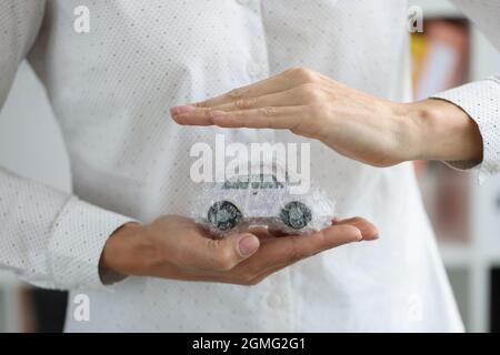 Le mani delle donne e l'automobile in sacchetto di imballaggio come primo piano di protezione Foto Stock