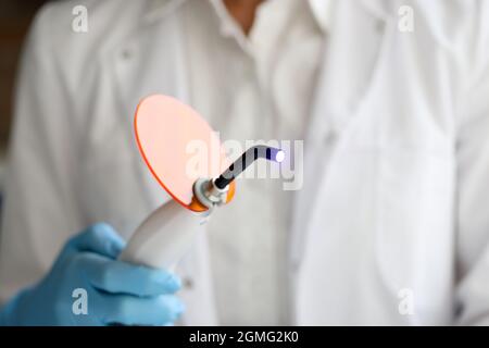 Lampada UV per polimerizzazione dentale e modello artificiale a mandibola. Primo piano lampada UV Foto Stock