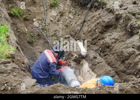 Operatore di servizio che fissa la rete idrica rotta. Concetto di riparazione del tubo fognario. Foto Stock