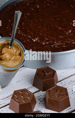 Piccole muffe di cioccolato per fare torta al miele brasiliano, accanto ad una lattina di dulce de leche (foto verticale). Foto Stock