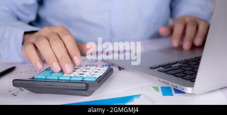 Le mani di uomo d'affari calcolano la tassa con la calcolatrice mentre il calcolatore del laptop sulla scrivania, la finanza di pianificazione dell'uomo e l'investimento con grafico e grafico, statistica Foto Stock