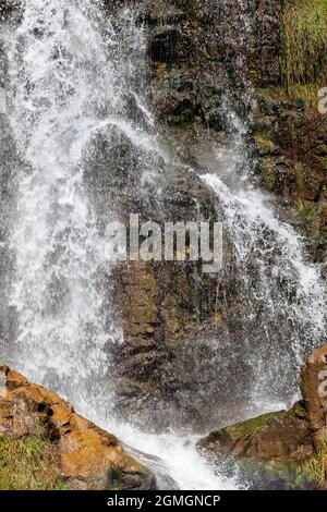 Primo piano di una potente cascata di alta qualità. Vista laterale di una cascata soleggiato nella natura selvaggia. Un grande flusso d'acqua si riversa verso il basso dal monte Foto Stock