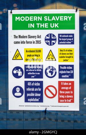 Schiavitù moderna nel Regno Unito, i cartelli a lavoro forzato di tipo PPE sulla recinzione dei cantieri edili, Justice in Motion, Lancashire Encounter anti-schiavitù performance parkour acrobati che indossano giacche ad alta visibilità o gilet intrattengono folle nel mercato di Preston Flag, Regno Unito Foto Stock