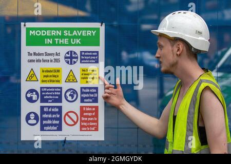 Modern Slavery Act, forzatura del lavoro segni di tipo PPE sulla recinzione in cantiere, Justice in Motion, Lancashire incontro prestazioni anti-schiavitù acrobati parkour indossando giacche hi-vis o gilet a Preston, Regno Unito Foto Stock