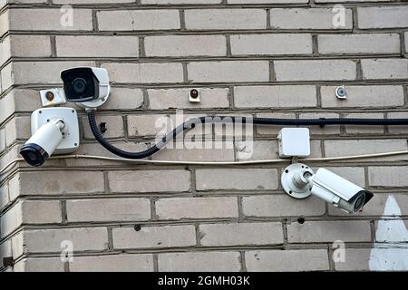 Le telecamere CCTV appendono sul muro di mattoni della casa Foto Stock