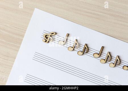 Note musicali in legno adagiate su un tavolo luminoso Foto Stock