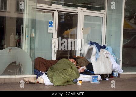 Uomo senza tetto che dorme in un sacco a pelo, Commercial Road Shopping Centre, Portsmouth, Inghilterra, Regno Unito. Foto Stock